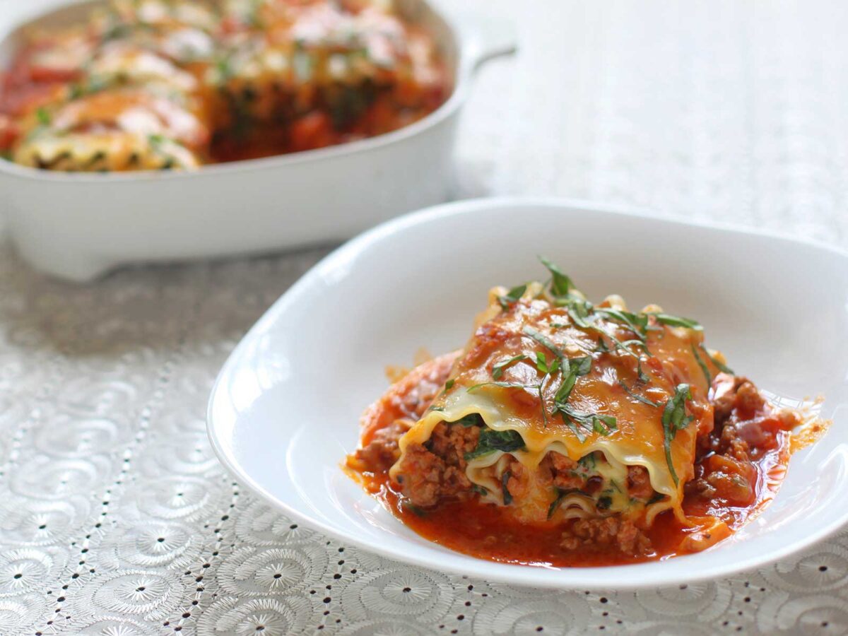 Lasagna roll-ups with crumbled sausage in tomato sauce