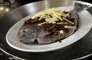 Covering pompano with black beans, ginger and garlic