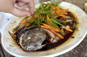 Topping steamed pompano with scallions and carrots