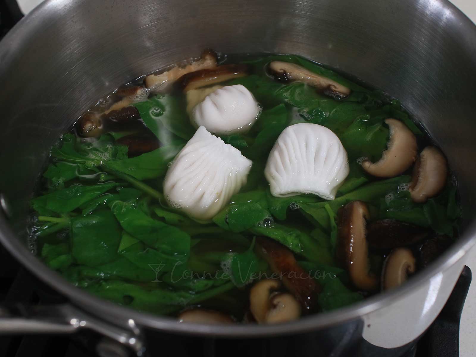 Frozen shrimp wontons with shiitake and spianch in pot