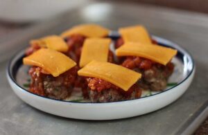 Meatballs topped with tomato sauce and cheese slices