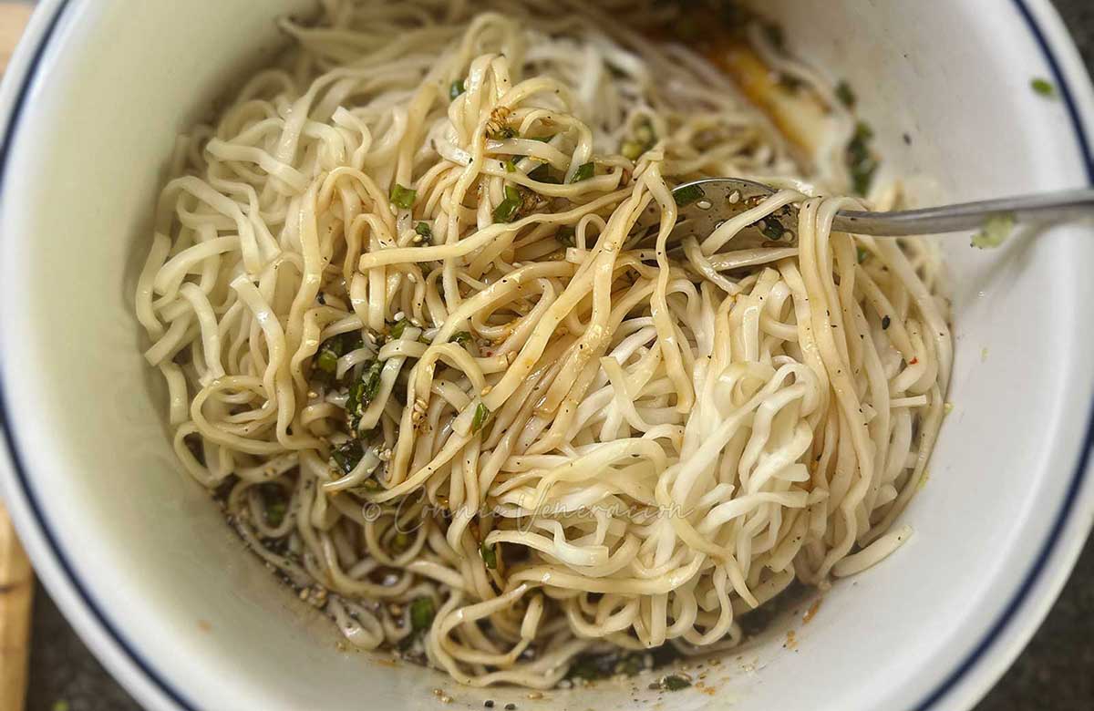 Tossing noodles in sauce with kimchi juice