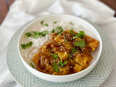 Lemongrass fried chicken garnished with sesame seeds and cilantro, and served over rice