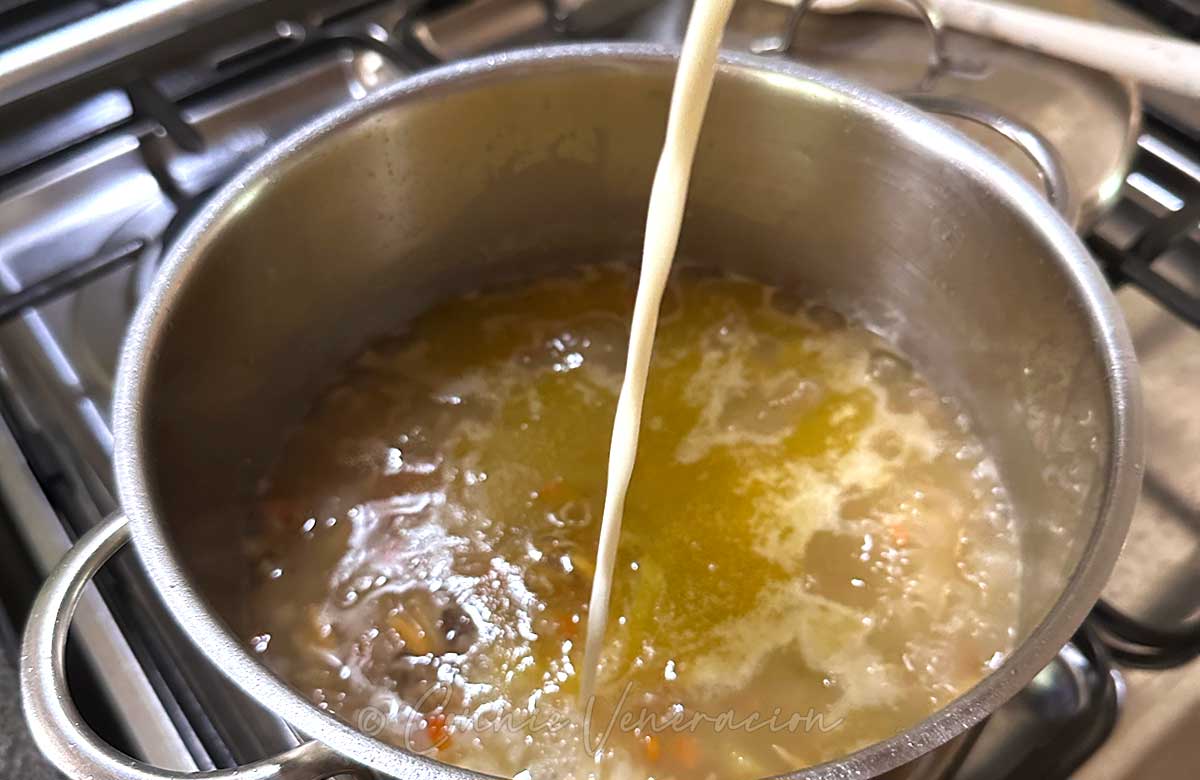 Pouring cream into simmering broth.