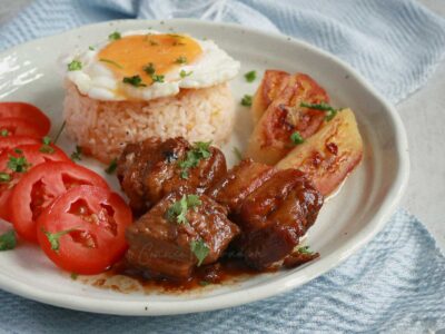 Slow cooker Filipino pork adobo with rice, egg, tomato slices and fried saba bananas