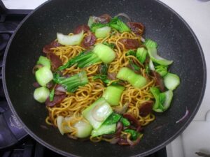Stir fried noodles, Chinese sausage and bok choy in wok