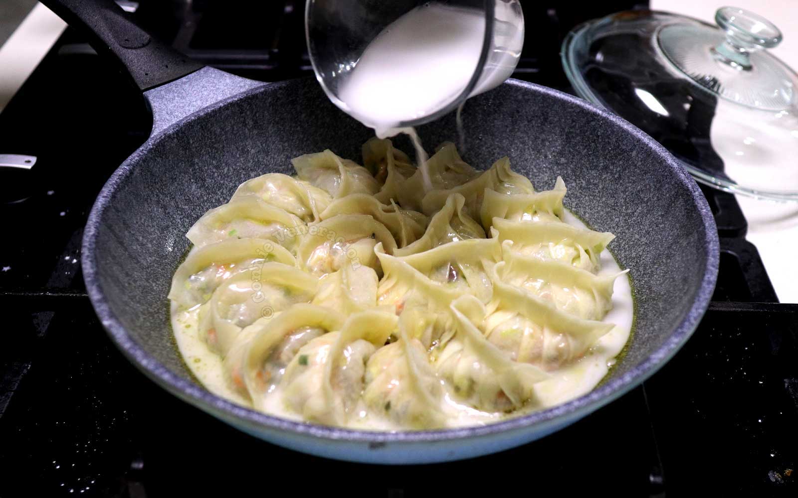 Pouring starch solution into pan with gyoza