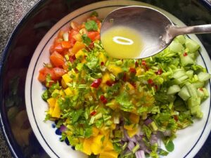 Adding calamansi juice to mango and tomato salad