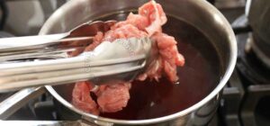 Dipping thinly sliced beef in simmering broth