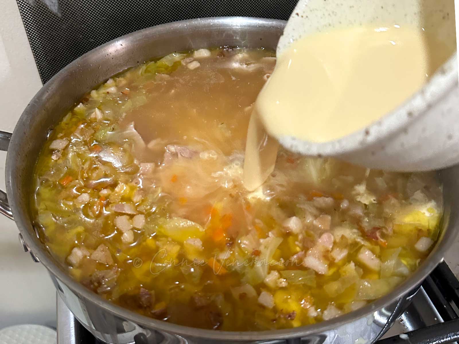 Pouring cream into pot to make sopas (Filipino chicken macaroni soup)