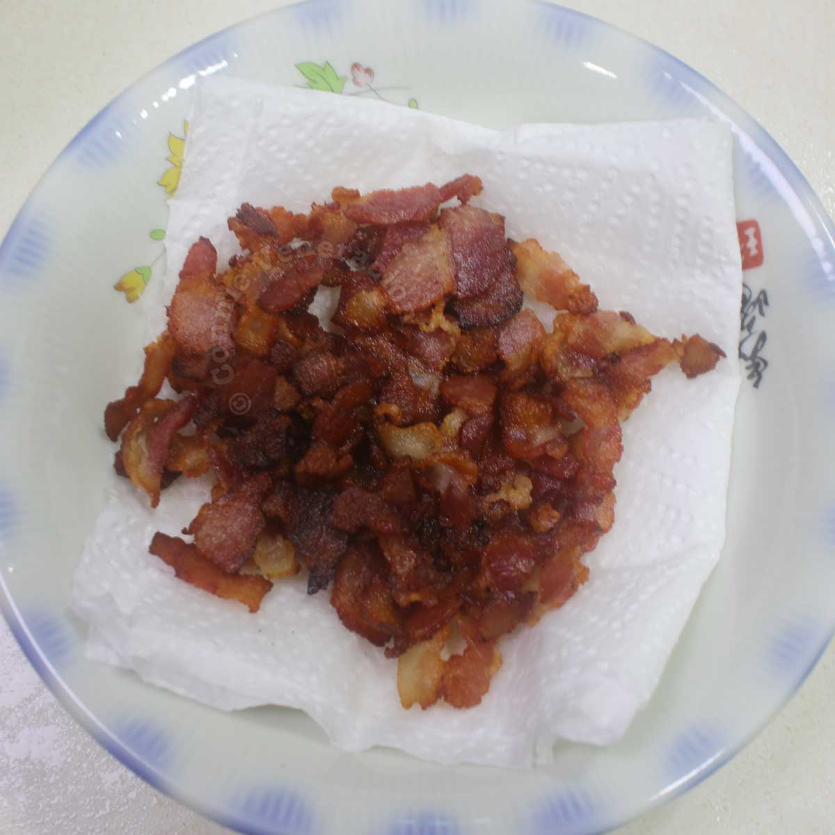 Chopped crispy bacon in bowl lined with paper towel