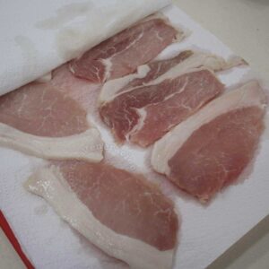 Pressing pork cutlets between stacks of paper towels