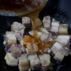 Pouring caramelized sugar over pork in wok