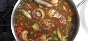 Adding browned oxtail to vegetables, wine and broth in pan