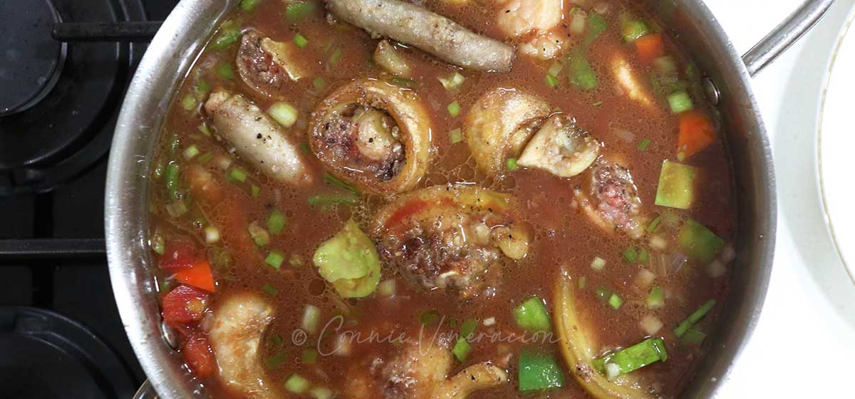 Adding browned oxtail to vegetables, wine and broth in pan