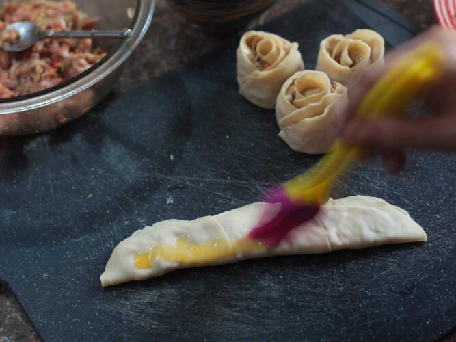 Brushing uncooked dumpling with egg