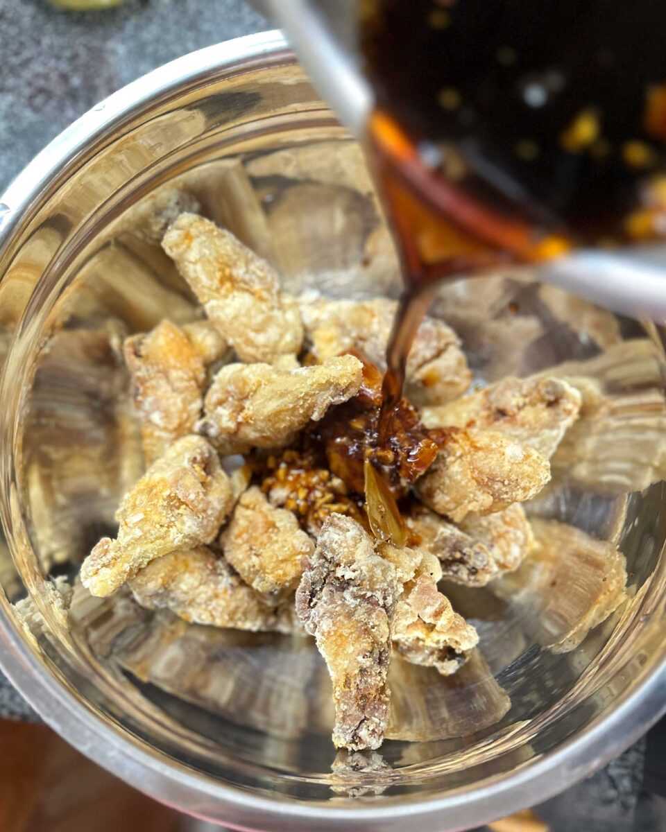 Glazing fried chicken wings with honey adobo sauce