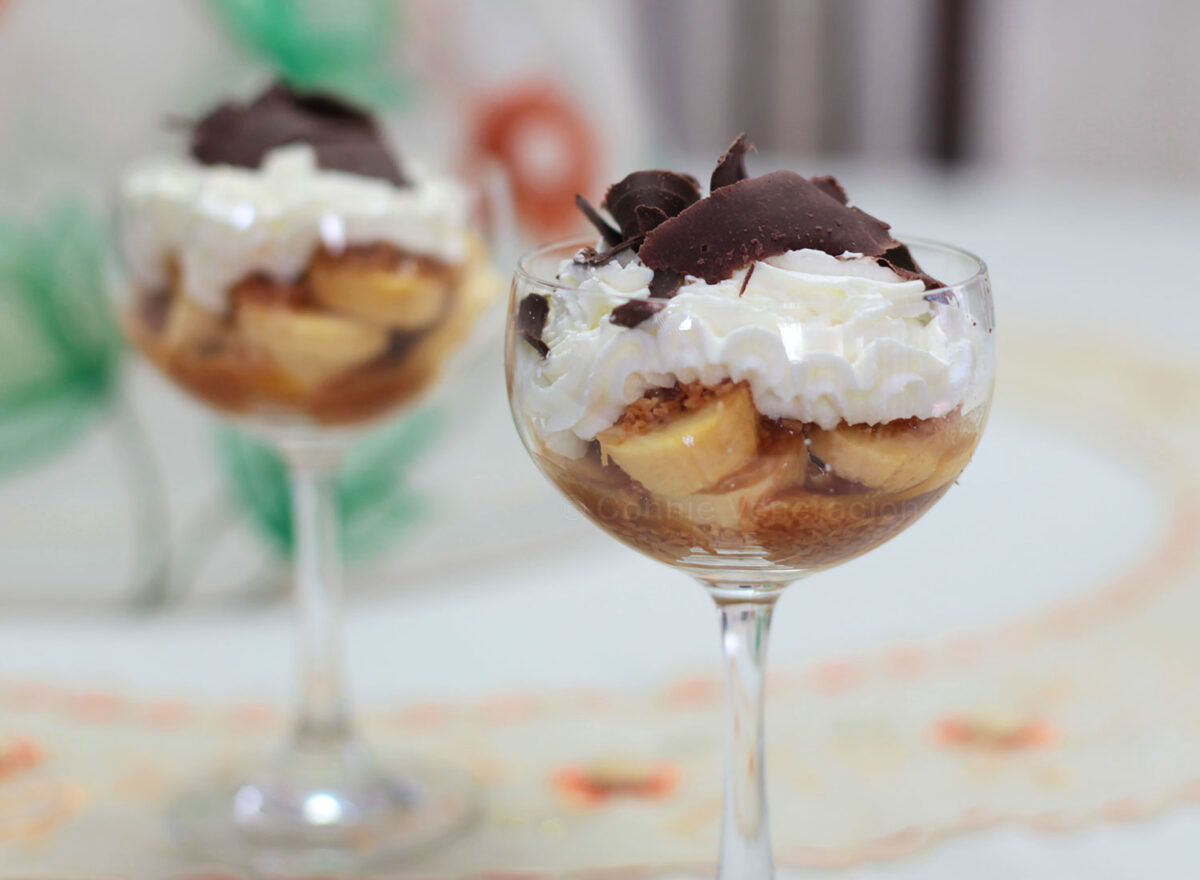 Banana slices, caramel, toasted coconut, whipped cream and shaved chocolate in glass