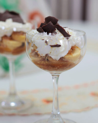 Banana slices, caramel, toasted coconut, whipped cream and shaved chocolate in glass