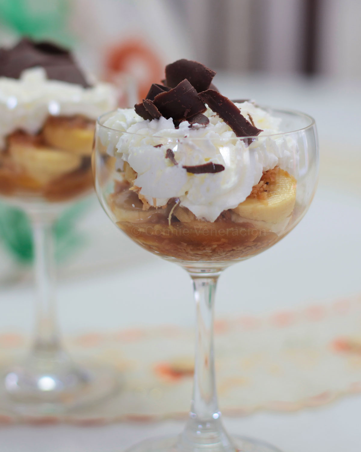 Banana slices, caramel, toasted coconut, whipped cream and shaved chocolate in glass