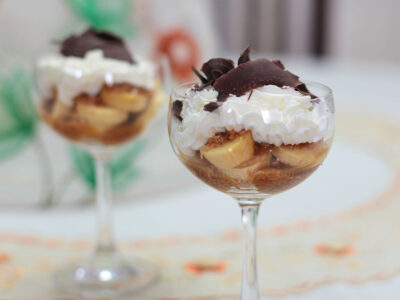 Banana slices, caramel, toasted coconut, whipped cream and shaved chocolate in glass