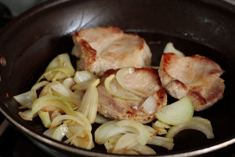 Browned onion and pork chops in pan