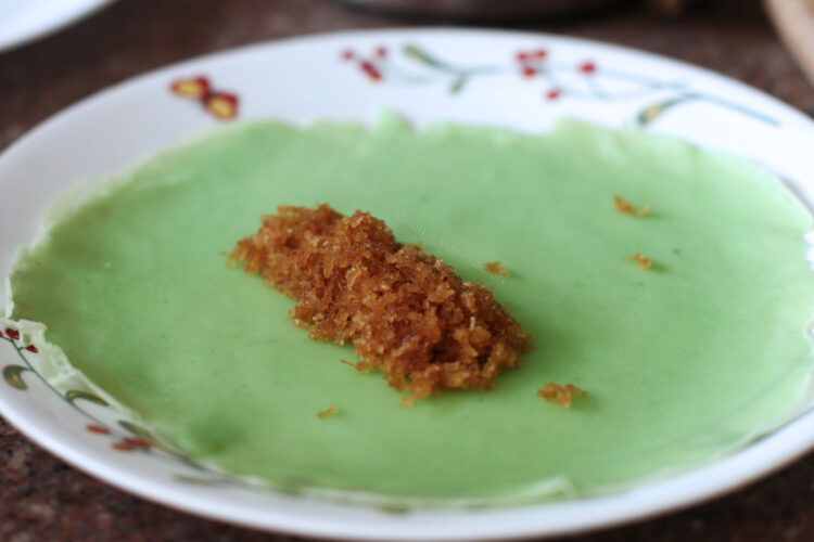 Assembling pandan crepes with palm sugar and coconut filling