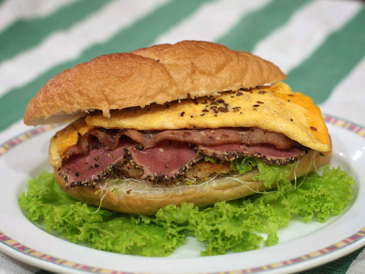 Meat lover's sandwich with chicken schnitzel, bacon, pastrami and cheese omelette