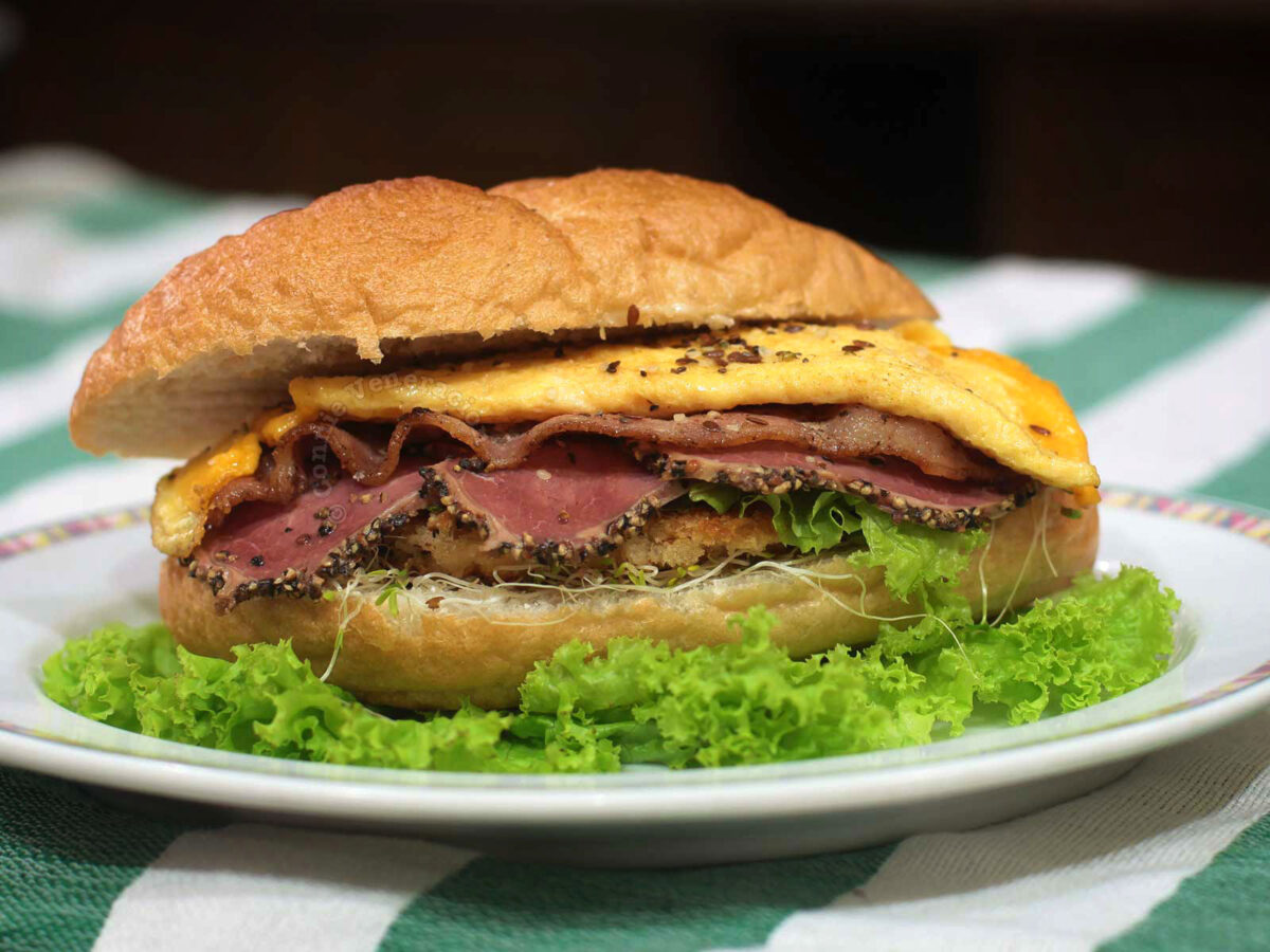 Meat lover's sandwich with chicken schnitzel, bacon, pastrami and cheese omelette