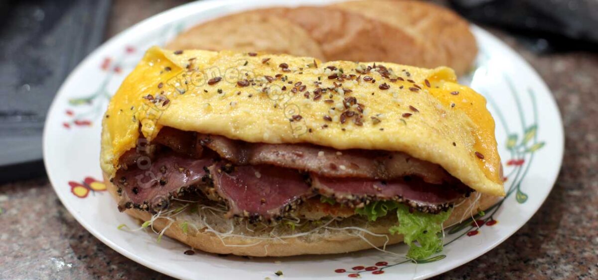 Meat lover's sandwich with chicken schnitzel, bacon, pastrami and cheese omelette