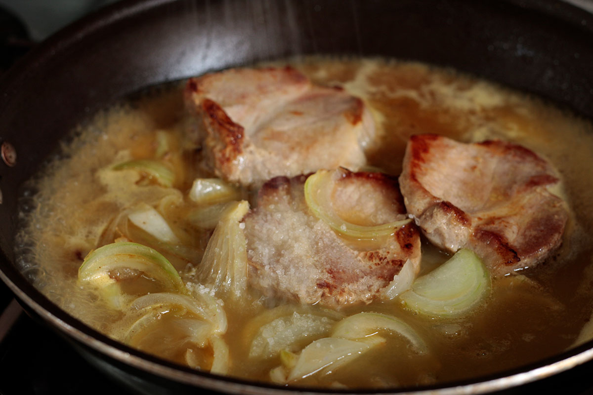 Seasoning pork chops in pan